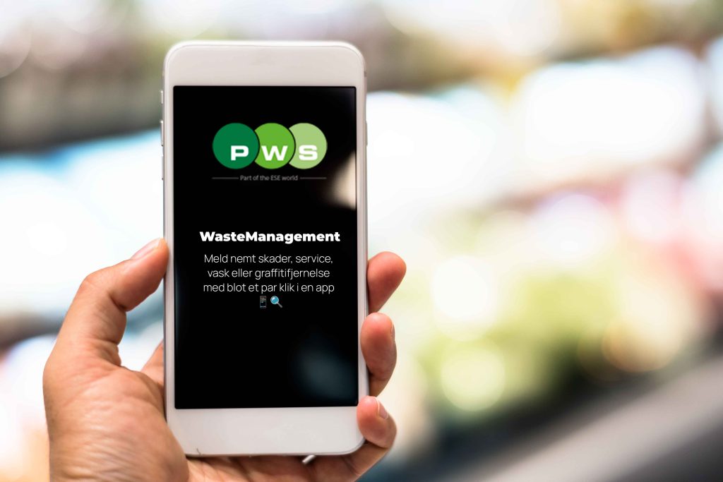 En hånd holder en mobiltelefon, der viser PWS WasteManagement-systemet, som bruges til at administrere affaldshåndtering effektivt.